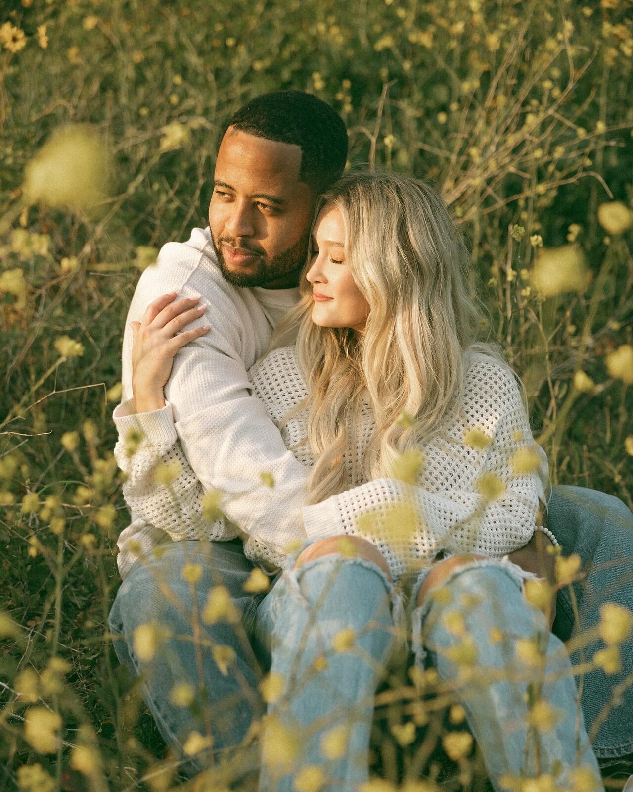Mariah and Petey sitting together in a field of wildflowers at golden hour